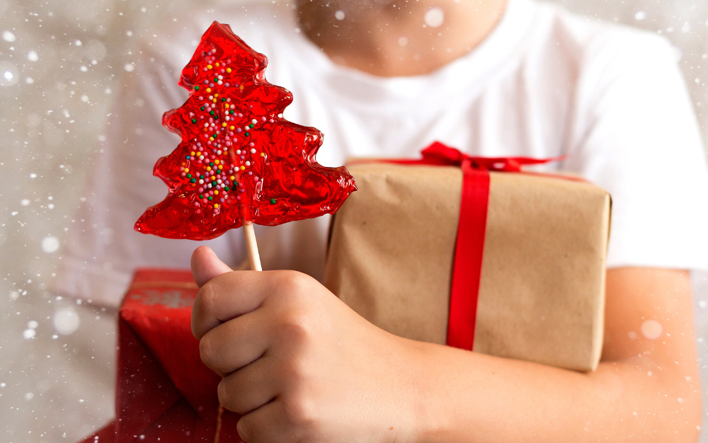 Child holding presents and a red lollipop