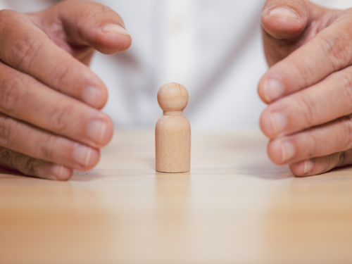 Hands protecting a small wooden figure