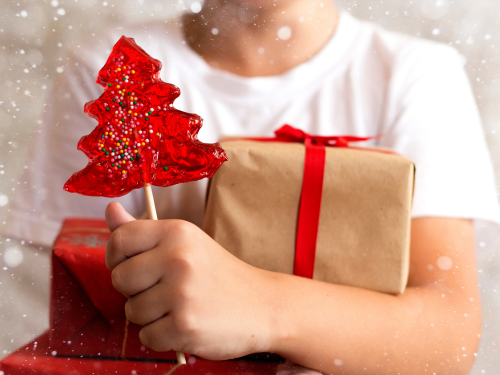 Child holding presents and a red lollipop